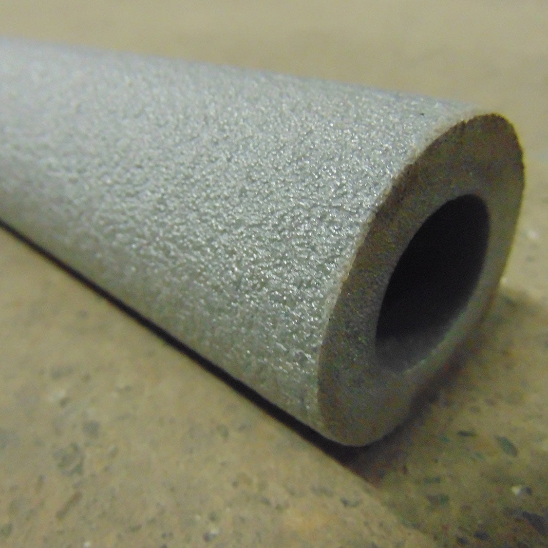 A rolled up piece of foam pipe insulation with a gray surface and a visible scored edge.