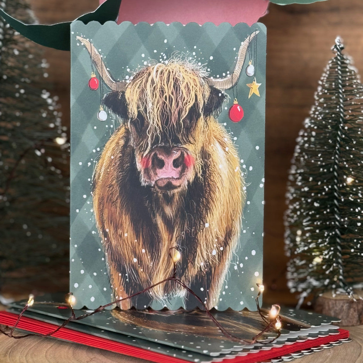 Alex Clark Christmas Highland Cow Doodles card pack of 5 showing an illustrated festive cow scene with white envelopes.