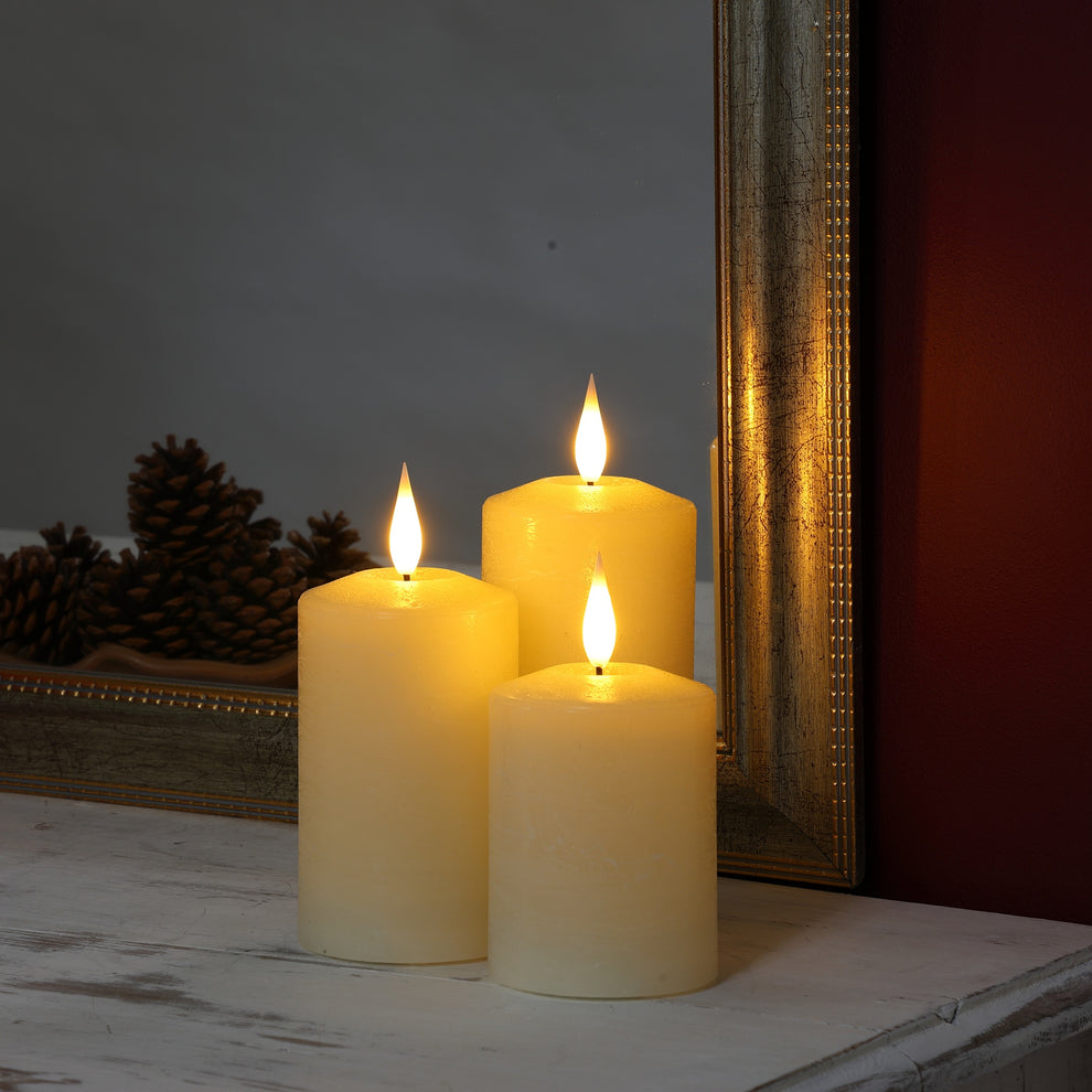Noma set of 3 ivory flameless real wax LED pillar candles flickering on a wooden surface