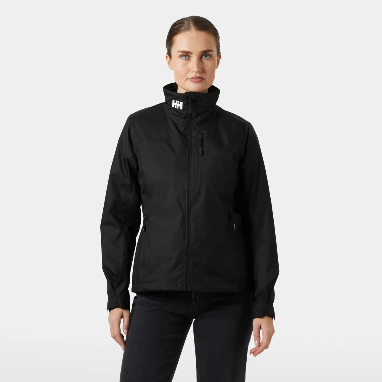 Front view of a woman wearing the black Helly Hansen Women's Crew Hooded Pile Jacket with zipped chest pocket and white HH logo printed on the collar.