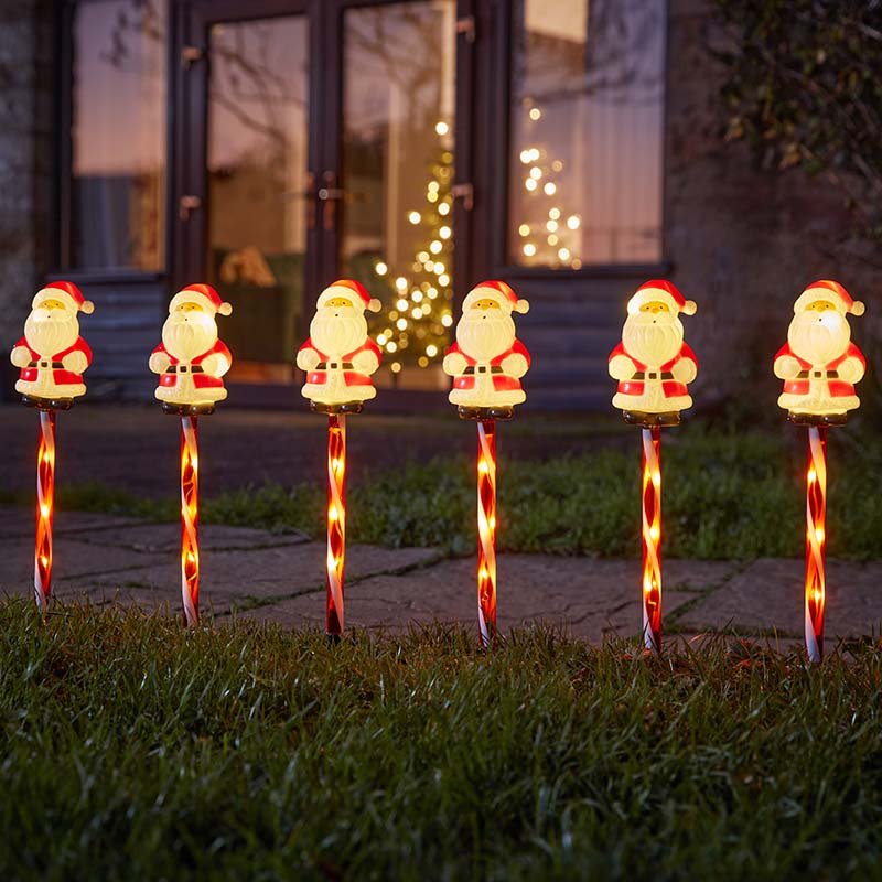 Smart Garden Santa Decor Stakes set of 6 lit up along a garden path in winter.</li>