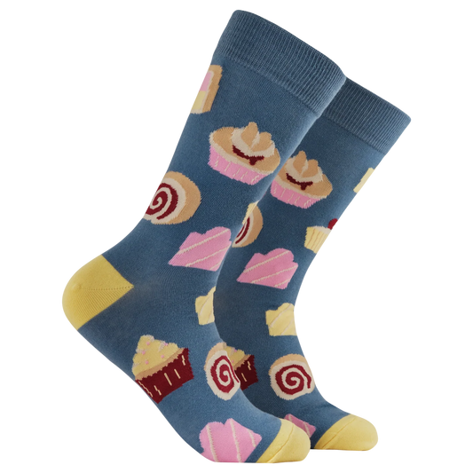Socktopus Cake Lover socks featuring a colourful pattern of cakes, cupcakes, and rolls on a blue background with yellow heels and toes