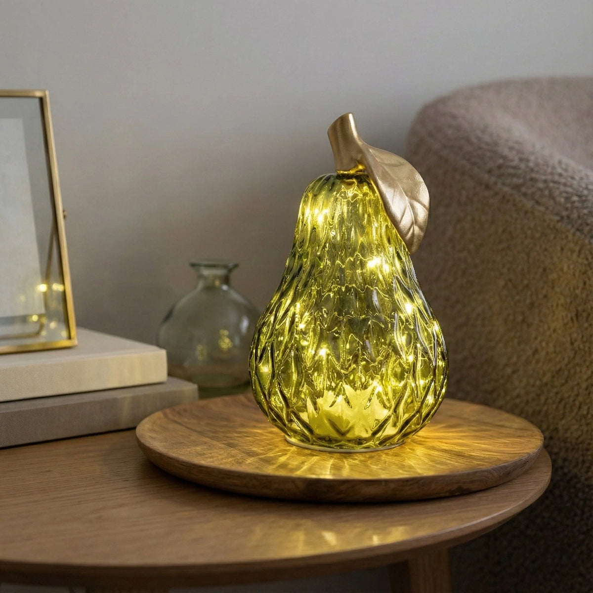 Candlelight Large Green Pear LED light ornament made of textured green glass with a golden stem and leaf