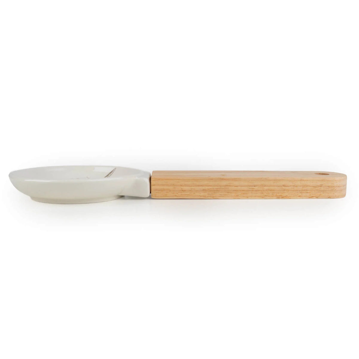 Candlelight Highland Cow spoon rest with glazed ceramic dish and natural wood handle resting on a wooden kitchen worktop