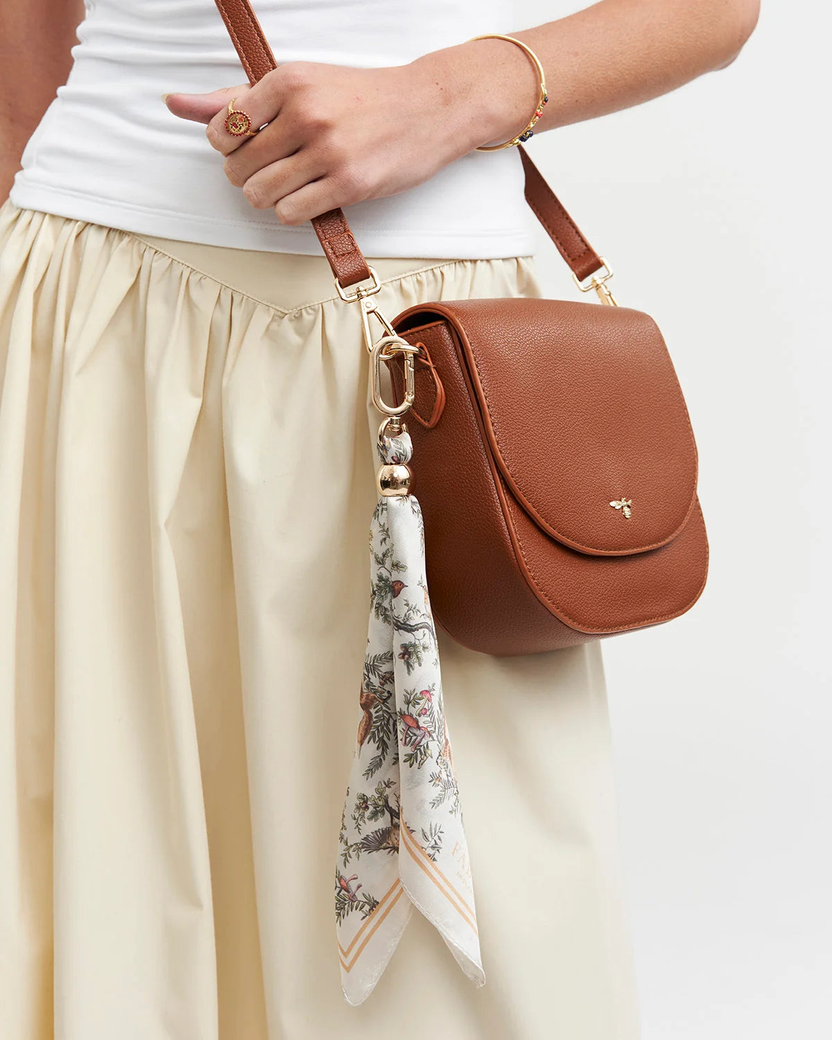 Fable Into the Woods Scarf Bag Charm attached to a brown leather handbag showing gold clip and printed scarf