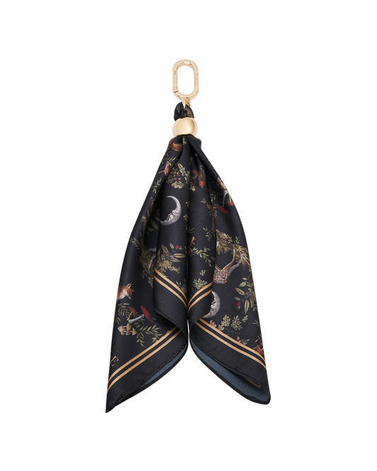 Fable Into the Woods Scarf Bag Charm attached to a brown leather handbag showing gold clip and printed scarf