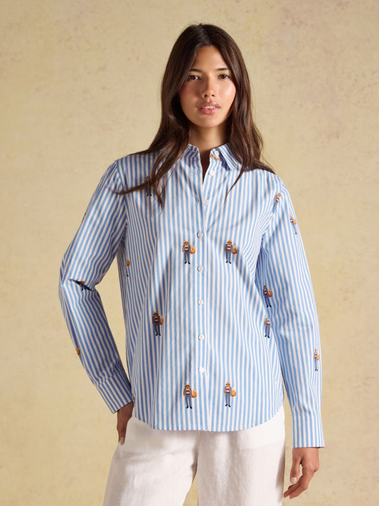 Woman wearing a blue and white vertical striped Joules classic cotton poplin shirt with a tailored fit and long sleeves.
