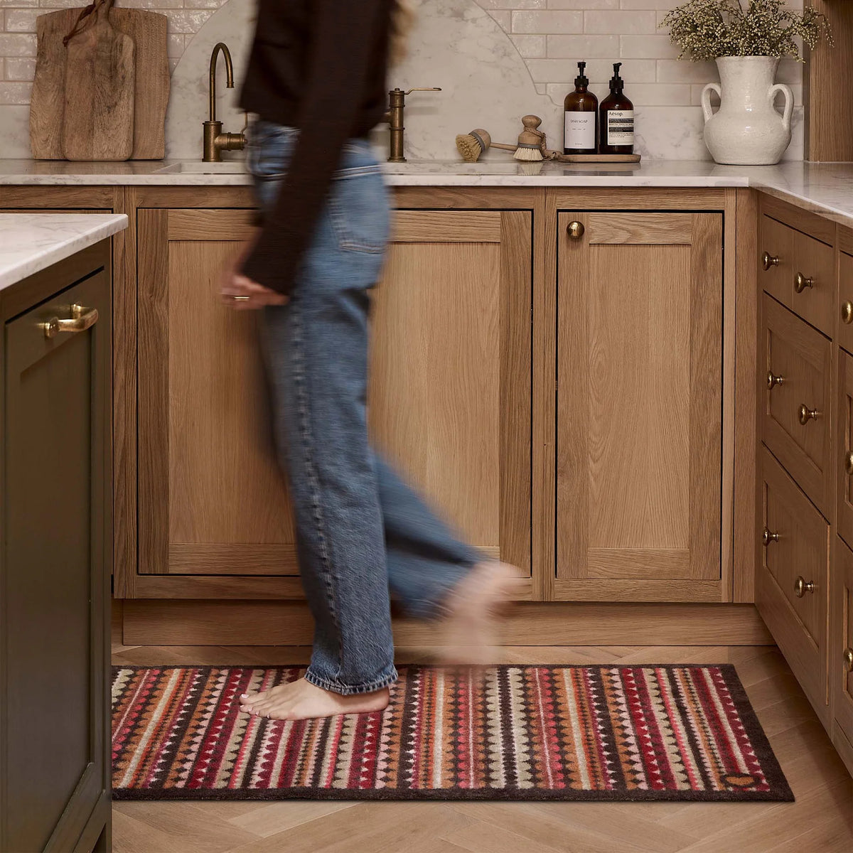Hug Rug Beady Stripe Earth washable runner mat with non-slip backing laid on a wooden kitchen floor