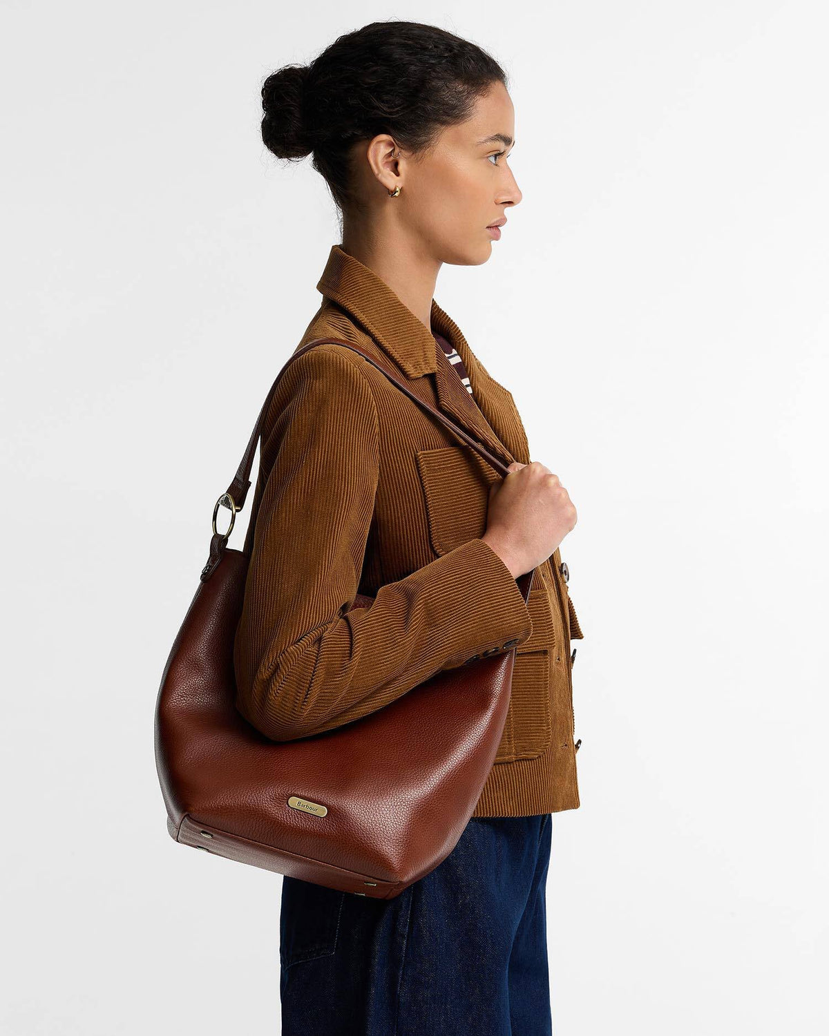 Barbour Cedar Large Leather Bucket Bag crafted from premium bovine leather, featuring a grab handle, detachable shoulder strap, and matte gold hardware.