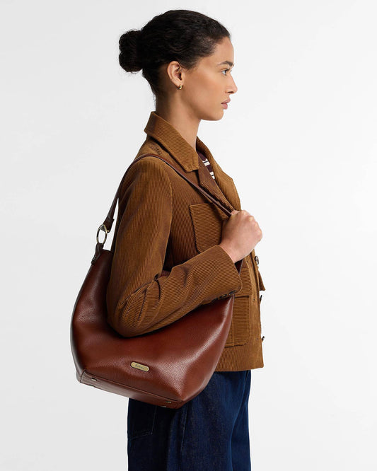 Barbour Cedar Large Leather Bucket Bag crafted from premium bovine leather, featuring a grab handle, detachable shoulder strap, and matte gold hardware.