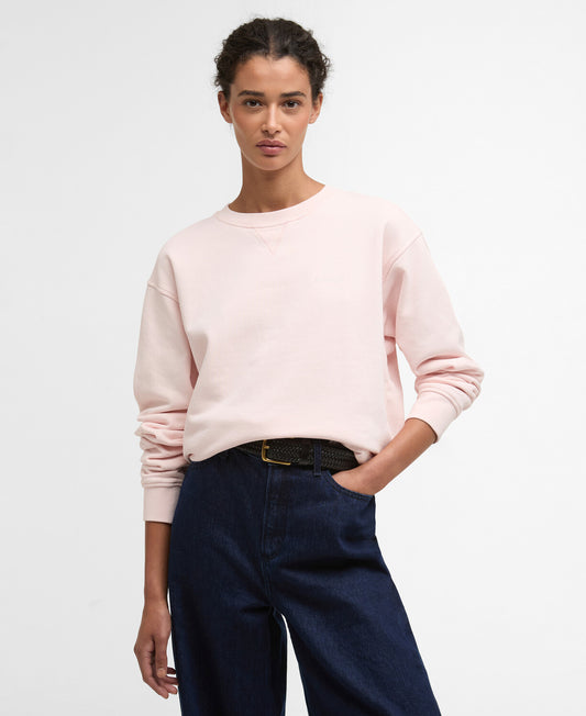 Front view of a woman wearing the Barbour Bede Oversized Sweatshirt in light pink, featuring a crew neck and dropped shoulders