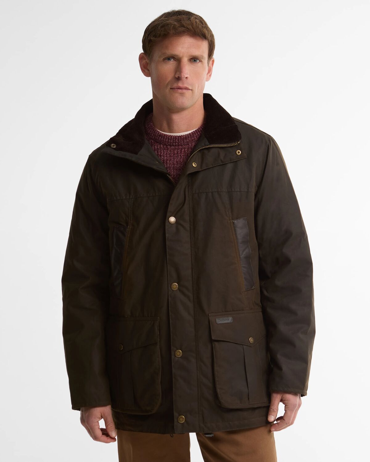 A man wearing the olive green Barbour Sandale Wax Jacket with a corduroy collar over a burgundy knit jumper.