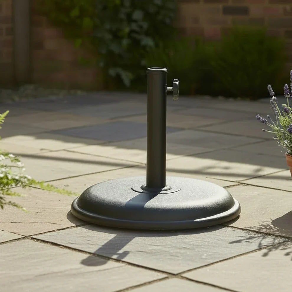 LG Outdoor compact 12kg black concrete parasol base positioned under a patio garden dining table.