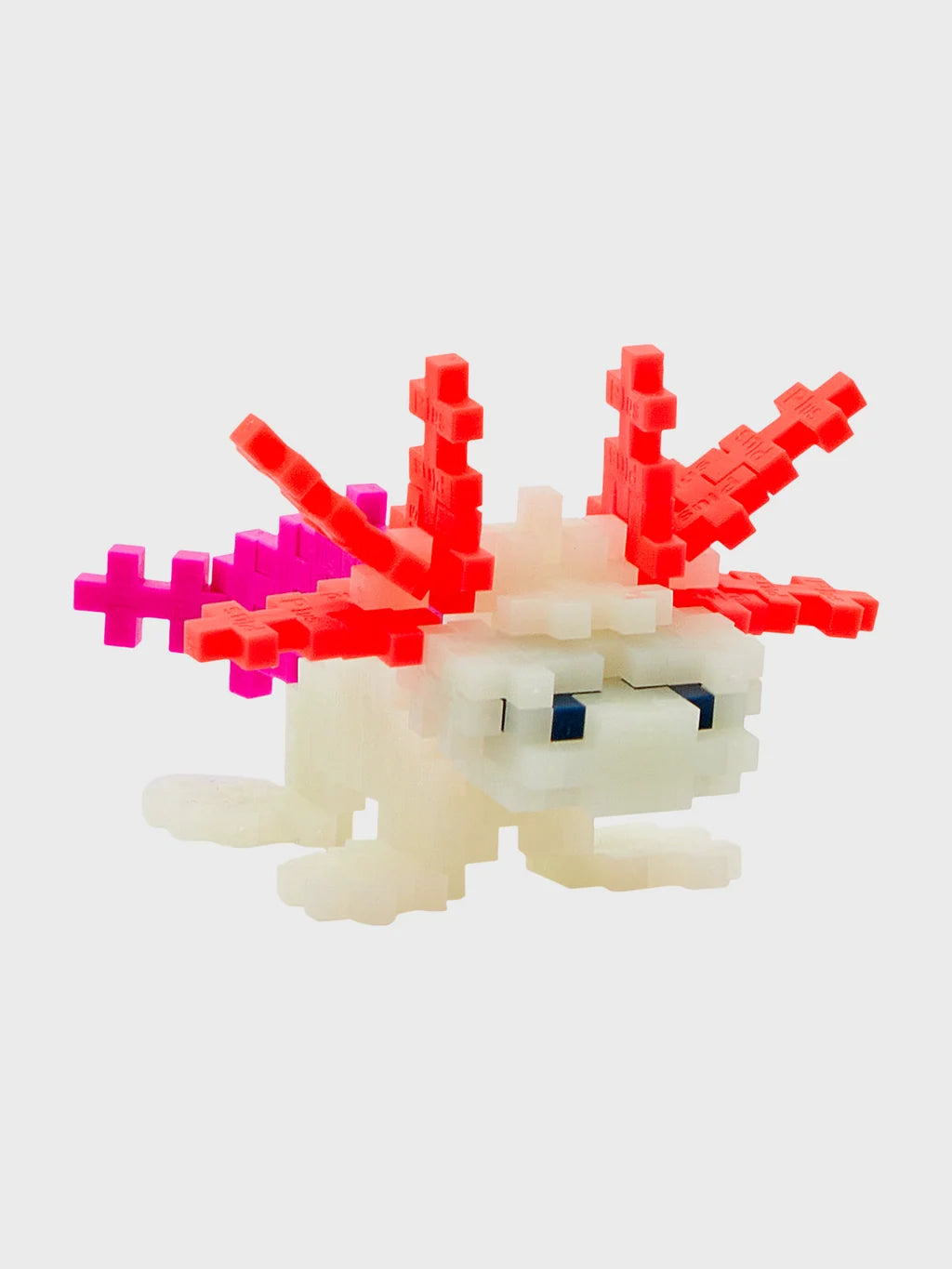Plus-Plus Axolotl tube packaging alongside a constructed glow-in-the-dark axolotl figure made from interlocking pieces.