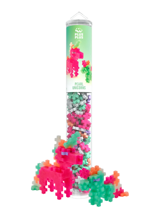 Plus-Plus Pearl Unicorns clear storage tube standing next to constructed pink and green toy unicorn figures.