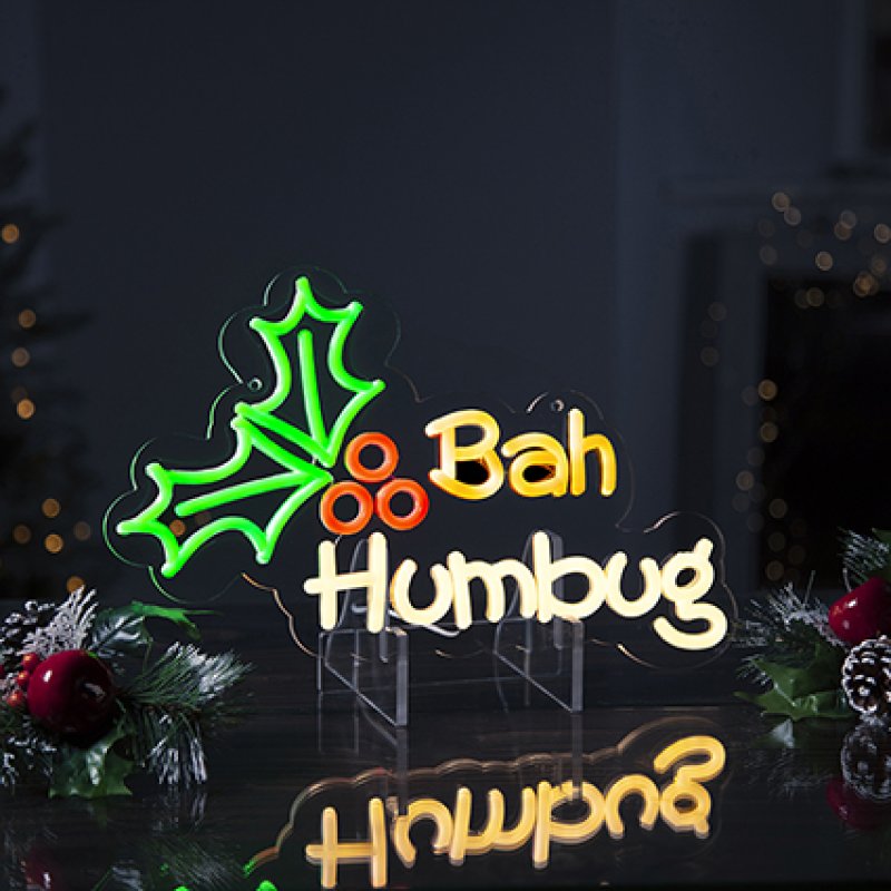 Premier 36cm Lit Bah Humbug neon hanging sign glowing with green holly leaves and yellow lettering.