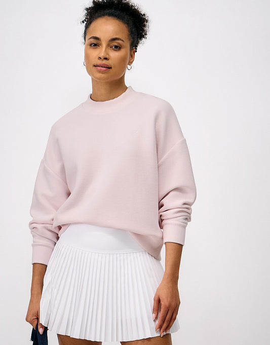 Front view of a woman wearing the light pink Crew Clothing Ottoman Cooldown Sweater with textured ribbed fabric and signature embroidered crossed oars on the chest.