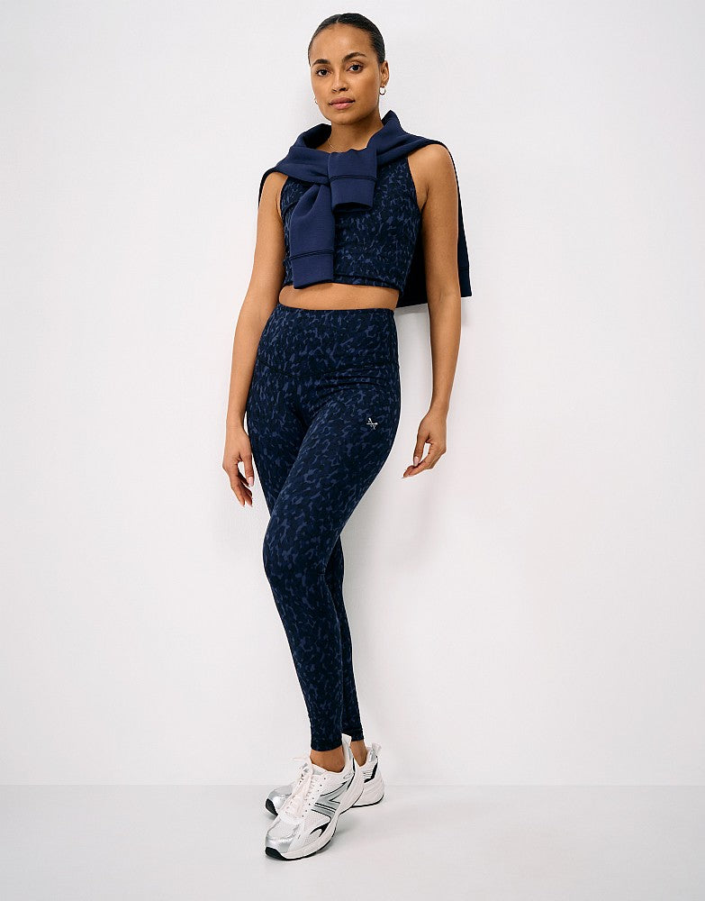 Full-length view of a woman wearing navy print Crew Clothing High Waisted Leggings with a matching cropped active top and trainers.