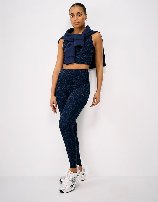 Full-length view of a woman wearing navy print Crew Clothing High Waisted Leggings with a matching cropped active top and trainers.