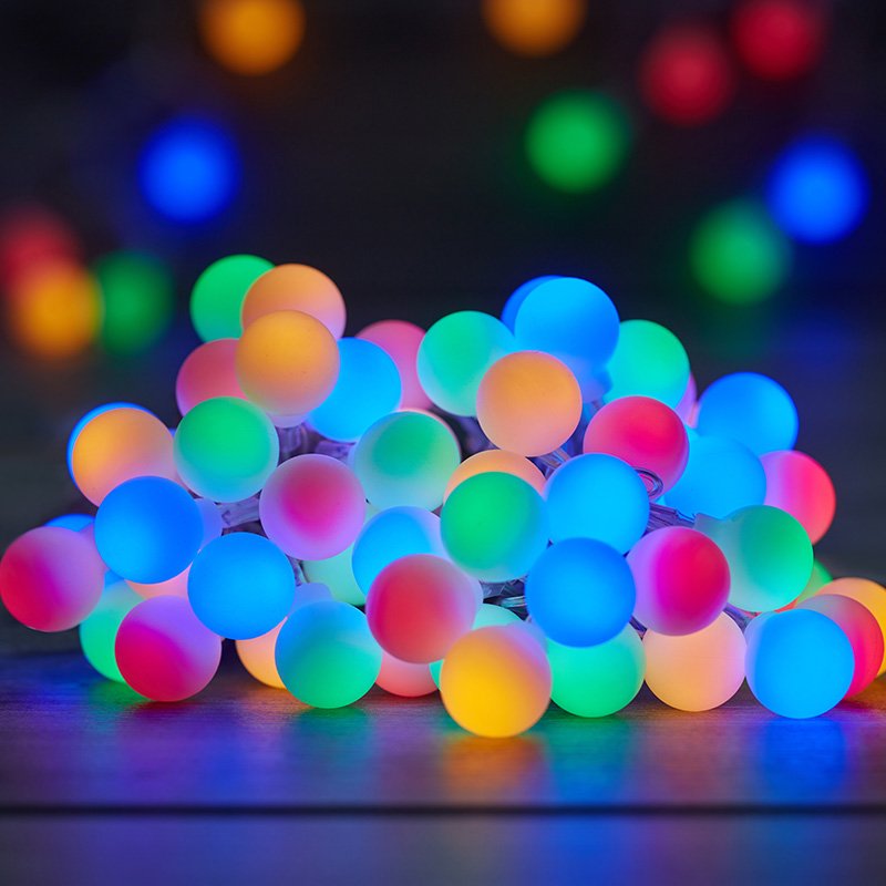 Smart Garden 100 multicolour LED frosted globe rechargeable string lights glowing on a table.
