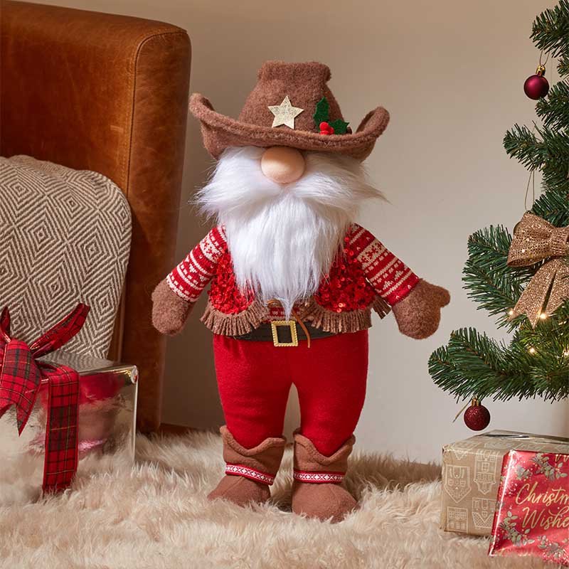 Smart Garden Howdy Gonk standing plush Christmas decoration wearing a brown cowboy hat and red sequin coat beside a Christmas tree.