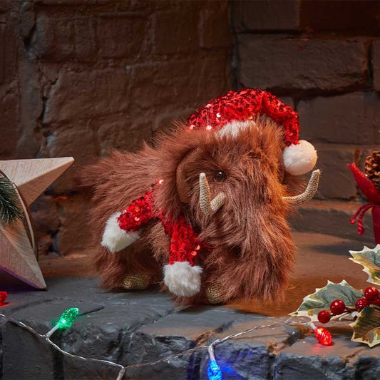 Smart Garden Merry Mammoth plush Christmas decoration with shaggy brown fur wearing a red sequin hat on a brick fireplace.