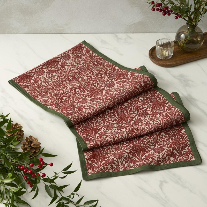 Spode Morris & Co. Bluebell red cotton table runner with deep green border folded on a table