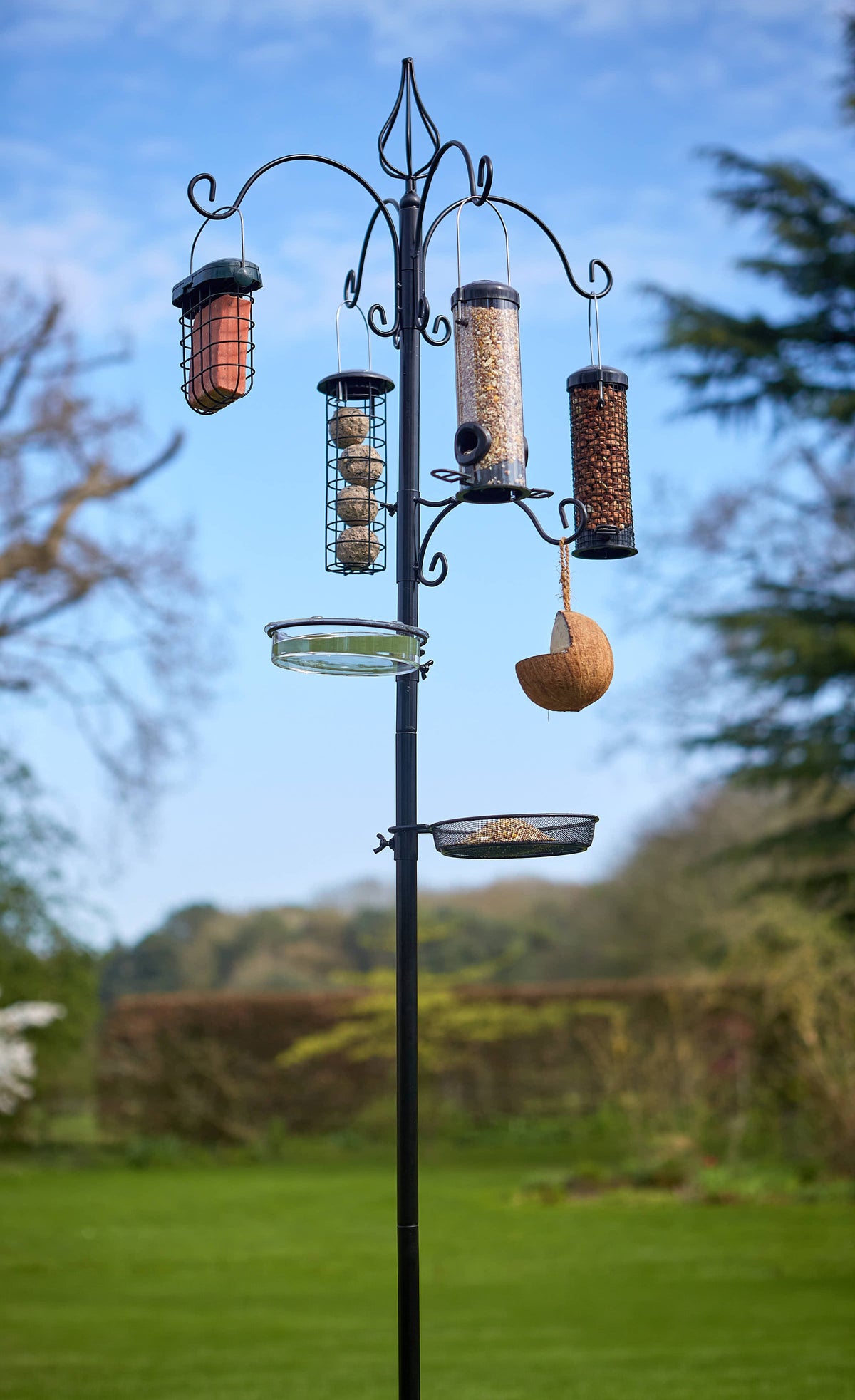 Tom Chambers Absolute Bird Feeding Station with multiple hanging feeders, water dish, and mesh seed tray set up on a lawn.
