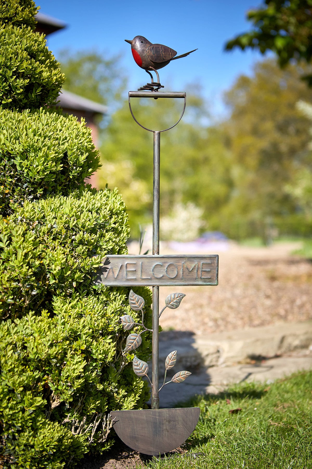 Tom Chambers Robin & Spade Plant Stake with robin motif and welcome sign set in a garden border.