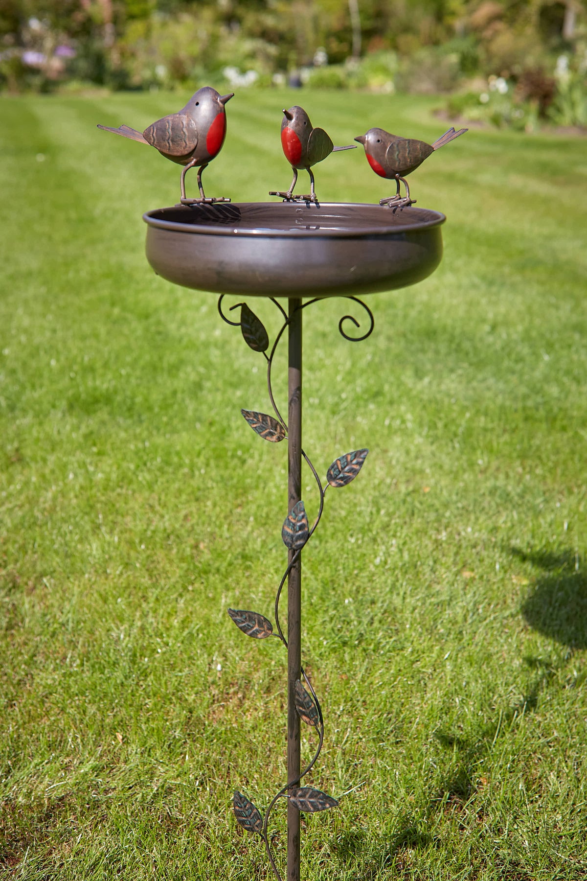 Tom Chambers Trio of Robins Bird Bath stake with three robin figures set on a garden lawn.