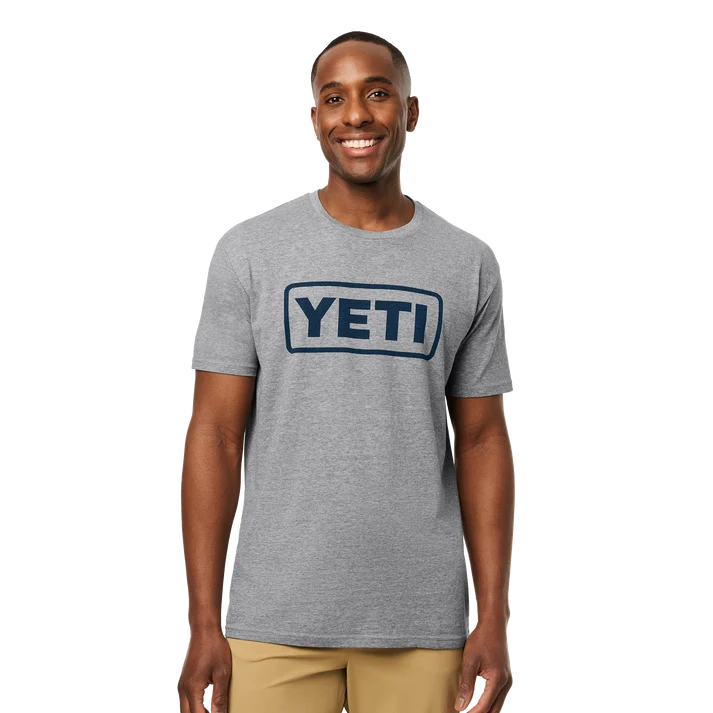 Men wearing YETI Full Logo Badge Short Sleeve T-Shirt in grey and black featuring front printed YETI badge logo