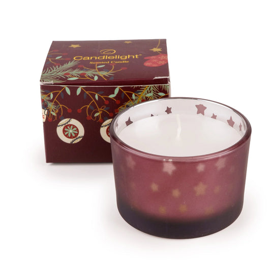 Candlelight red single scented candle in a star decorated glass vessel next to its festive stockings and baubles gift box