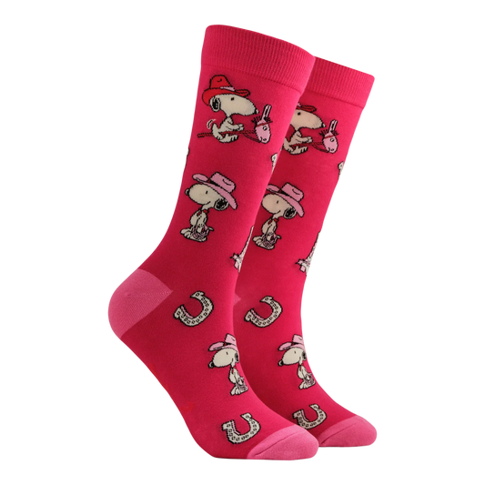 Socktopus In the Saddle Peanuts socks featuring Snoopy wearing a cowboy hat with horseshoes on a bold pink background