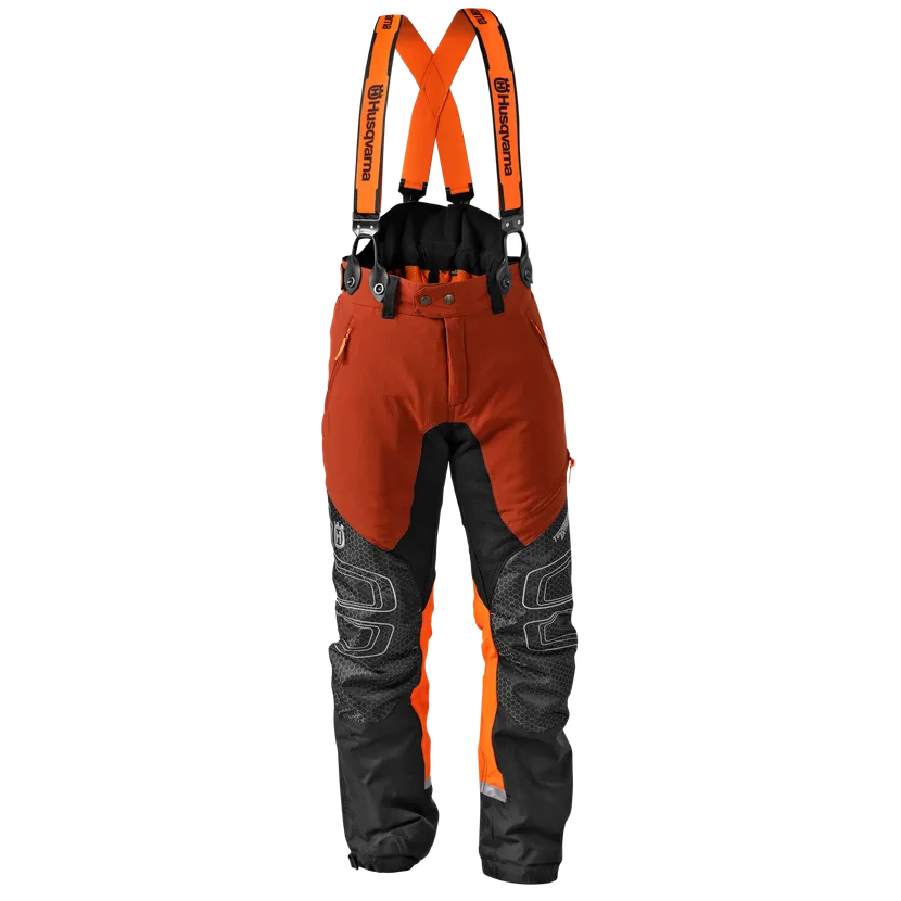 Husqvarna Technical Extreme Chainsaw Trousers in high-visibility orange and black, featuring reinforced Tech-Knee panels, deep utility pockets, and attached branded suspenders.