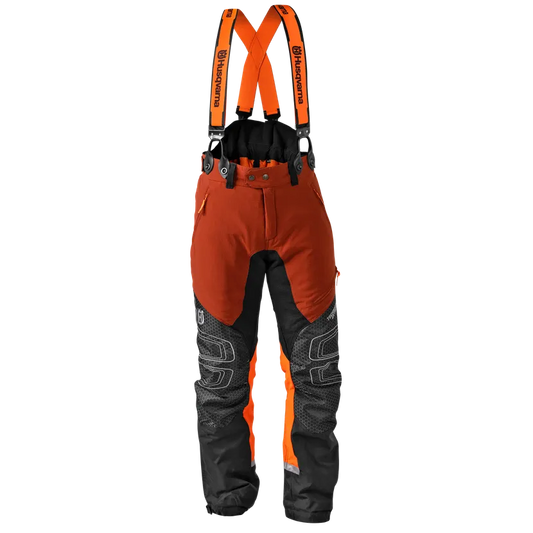 Husqvarna Technical Extreme Chainsaw Trousers in high-visibility orange and black, featuring reinforced Tech-Knee panels, deep utility pockets, and attached branded suspenders.